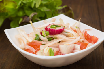 Fresh salad with cabbage, radish and tomato. Wooden background. Top view. Close-up