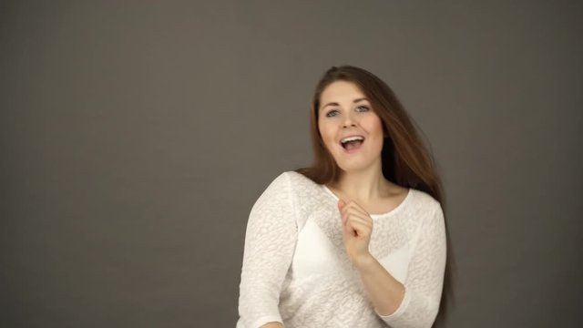 Woman having fun dancing, joyful young female showing positive expression, studio shot grey wall background 4K
