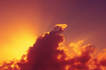 Fototapeta na wymiar Cielo rosso al tramonto con raggi di sole che spuntano dietro ad una nuvola