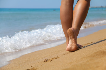 Young female walking on the sandy beach on sunny day