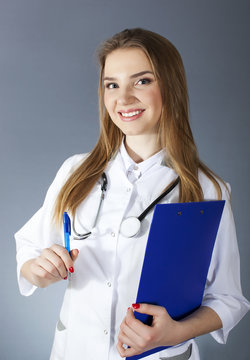 Attractive smiling woman doctor, nurse holding  paper tablet and pen