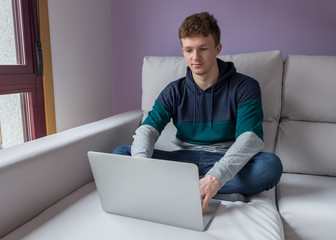 young man sitting on the sofa in front of a laptop