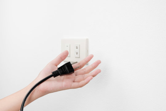 Plug on hand or unplug and outlet on white wall background , electric shock