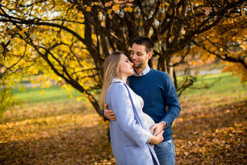 Pregnant woman and man posing at autumn park