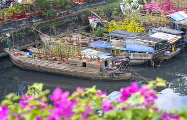 Fototapeta na wymiar Ho Chi Minh City, Vietnam - January 26, 2017: Flowers boats at flower market on along canal wharf. This is place where farmers sell apricot blossom and other flowers on Lunar New Year in Vietnam