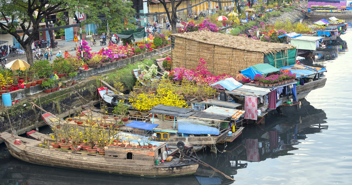 Ho Chi Minh City, Vietnam - January 26, 2017: Flowers boats at flower market on along canal wharf. This is place where farmers sell apricot blossom and other flowers on Lunar New Year in Vietnam