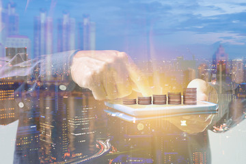 Double exposure of businessman hand touching digital tablet over night cityscape