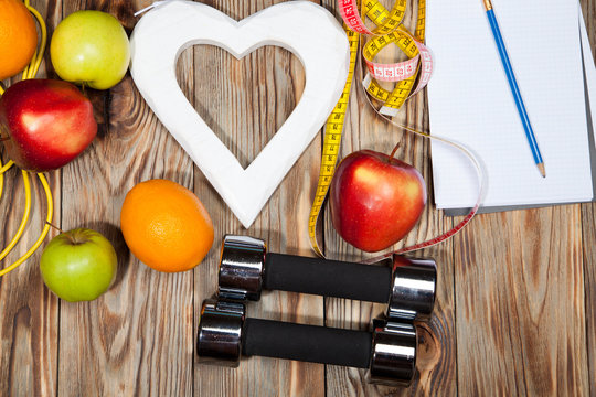 Heart, apples and oranges, diet, healthy , dumbbells  a jump rope on  wooden background