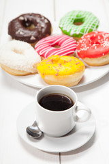 Cup with coffee and donuts on a white wooden table