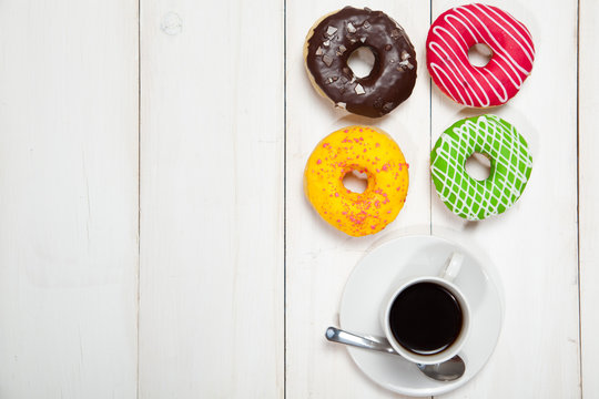 Cup with coffee and donuts on a white wooden table