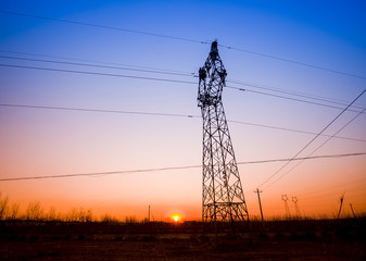 Fototapeta premium The silhouette of the evening electricity transmission pylon