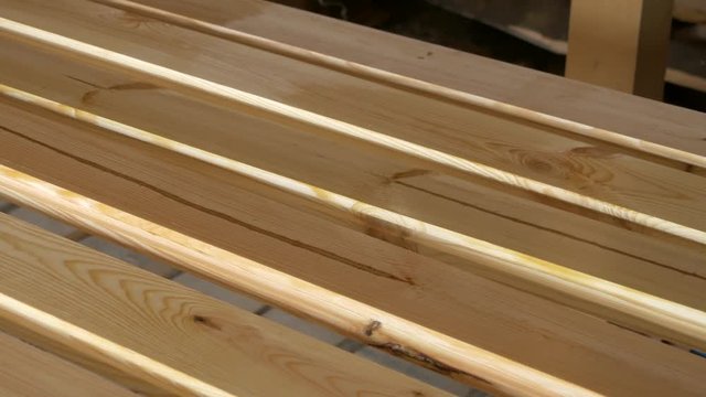 Impregnation and imbibition of diagonally arranged wooden bars with a brush. Construction and painting works from wood. Varnishing and gloss of wood in the shop. Reflection of pine material.