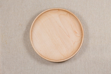 Empty wooden plate in linen background.