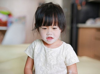 Portrait of cute little smile girl with baby powder on her face. Talcum concept.