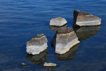 Striped stones in blue clear water on shallow