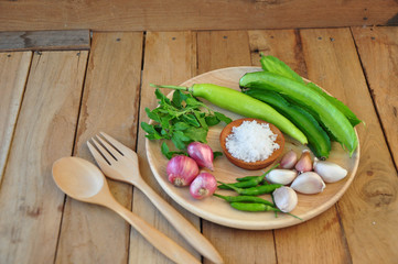 ingradian. vegetable ingradian. red onion, winged bean, besil leaf, garic, chilli and salt is on a wooden plate.