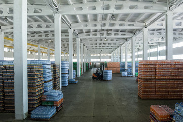 panoramic view of a large warehouse with drinks in plastic bottles with loading machines