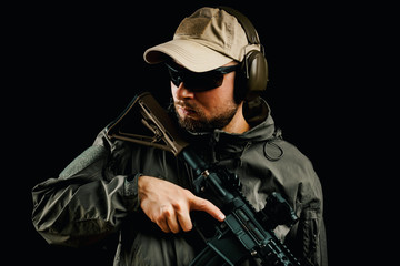 Fototapeta premium man in cap and jacket keeps assault rifle