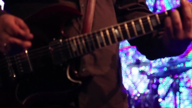 guitarists on stage playing an electrical guitar