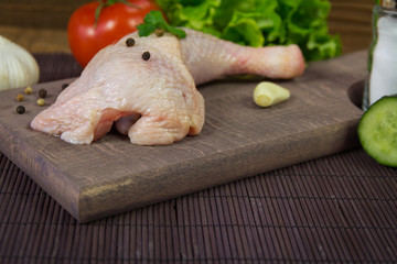 Raw chicken leg on cutting board on wood table
