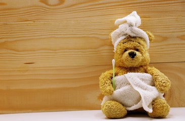 Bear in day spa on wooden background, Bear is cleaning ear with cotton bud.