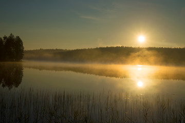 Fototapeta na wymiar Foggy sunrise on the forest lake. August morning. Finland
