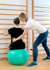 Physiotherapie Praxis Haltungsschulung mit Stiftkontrolle auf Gymnastikball an der Sprossenwand