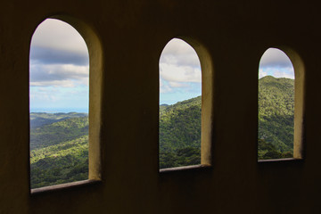 Fototapeta premium Beautiful view of the jungle and the Atlantic ocean through three old tower windows in Puerto Rico.