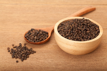 black peppercorns in wooden bowl