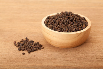 black peppercorns in wooden bowl