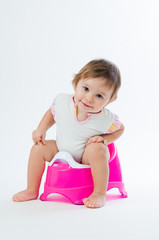 Little smiling girl sitting on a pot. Isolated on white background.