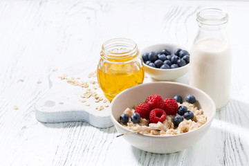 delicious homemade oatmeal with berries for breakfast on white background