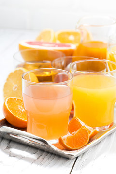 assortment of fresh citrus juices on white table, vertical closeup