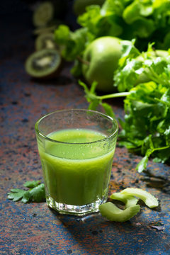 glass of juice of celery and greens on blue background, vertical