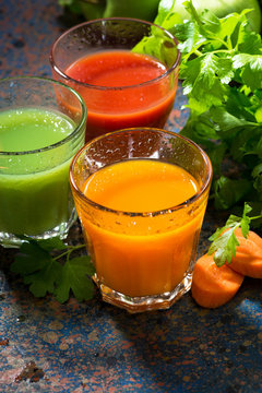 glasses of fresh vegetable juice from carrots, tomatoes and herbs, top view, vertical