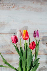 Old wooden background with tulips in vase