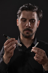 Portrait of man who is decided to quit smoking cigarette in favor of electronic cigarette. 
