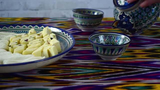 Hand pouring tea into ceramic bowl in cental asia cafe, Uzbekistan