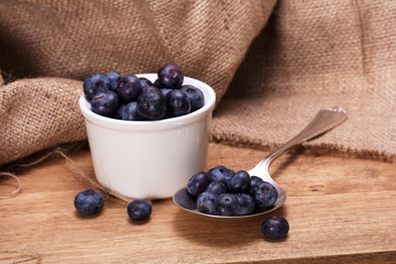 Pot of blueberries with spoon on a rustic background