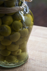 Green olives from Spain in glass jar on the wooden background