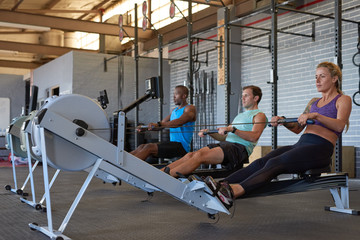 Fototapeta na wymiar People working out in gym on rowing machines