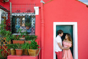 Tender couple in love near a typical Burano red house, Venice, Italy