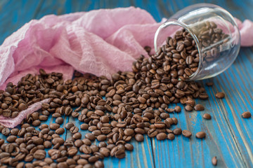 Close-up of coffee cup with roasted coffee beans on wooden background.