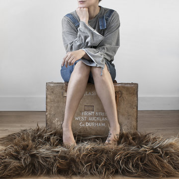 Woman With Bare Legs Sitting On A Suitcase At Home