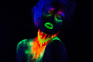 Beautiful extraterrestrial model woman with blue hair and green lips in neon light. It is portrait of beautiful model with fluorescent make-up, Art design of female posing in UV with colorful make up