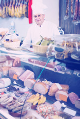 Portrait of  male seller posing with wursts in butchery