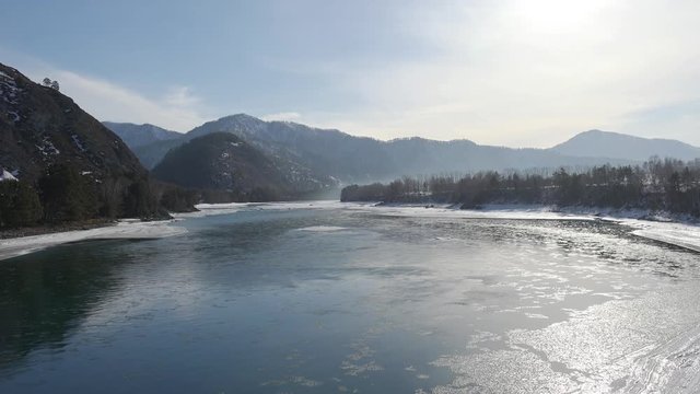 Aerial view on Altai river Katun with  floating of ice  in water and mountains on background in winter season