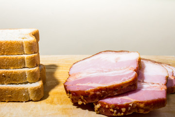 Raw smoked bacon slices with bread on wooden board