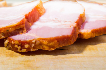 Raw smoked bacon slices on wooden board