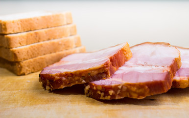 Raw smoked bacon slices with bread on wooden board